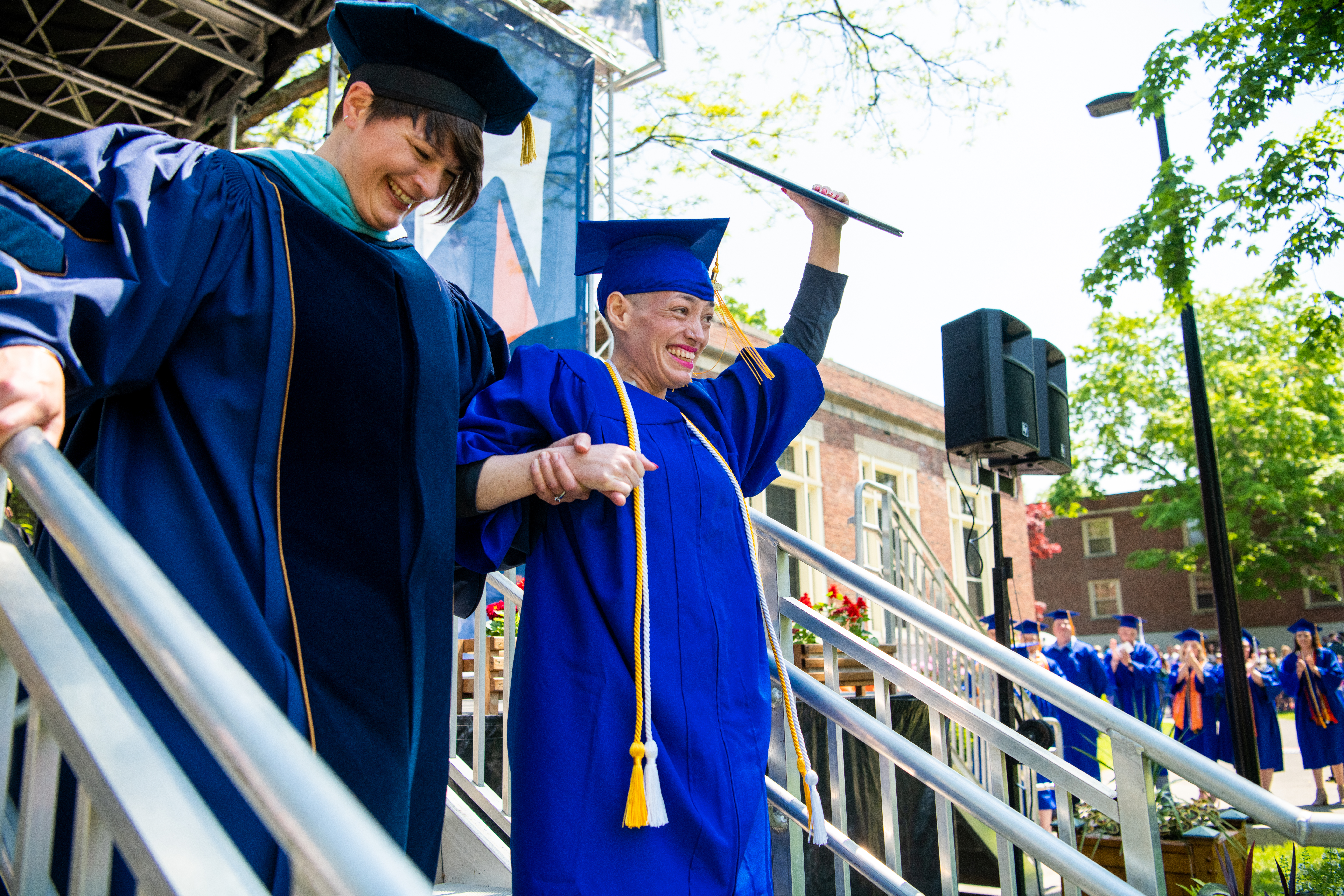 A student receiving assistance crossing the stage at a Commencement ceremony.